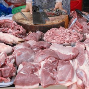 woman wearing conical hat selling raw meat